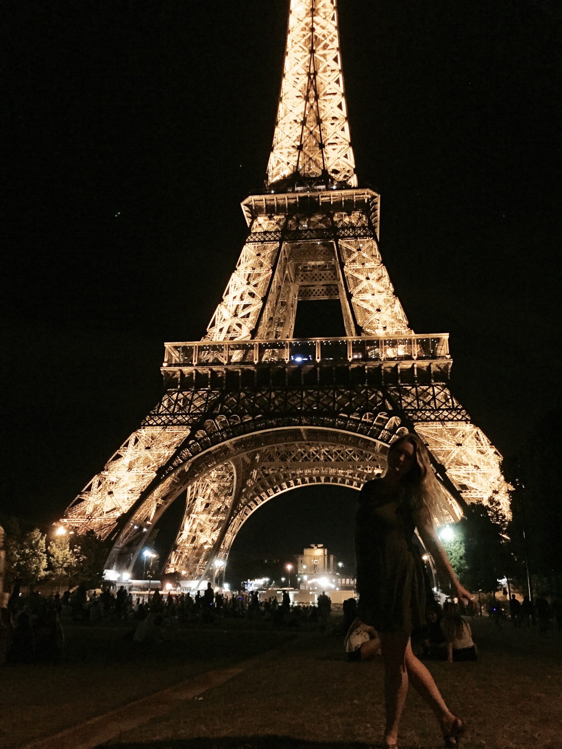 woman in front of the Eiffel tower in Paris, France at night
